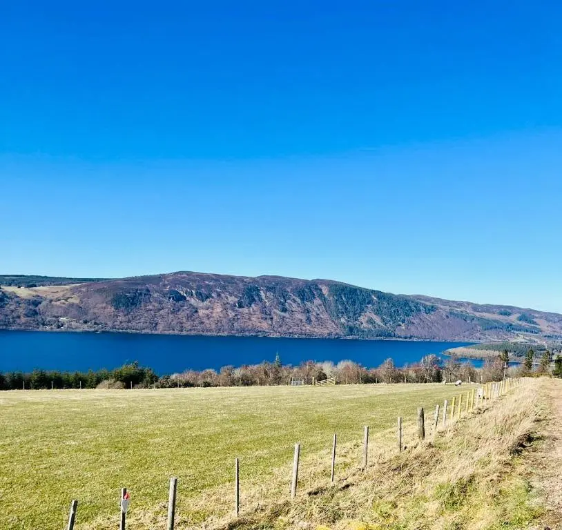 a fence in a field with a lake in the background at 1 Loch Ness Heights in Inverness