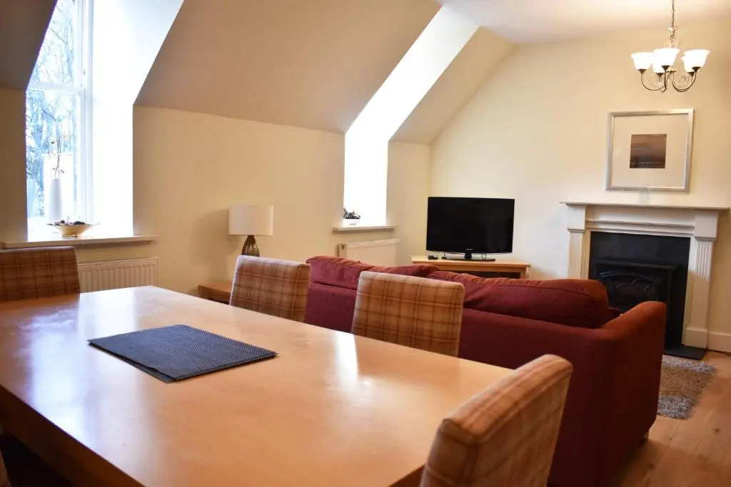 a living room with a table and a couch at The Ross 2 bedroom apartment in historic Abbey in Fort Augustus