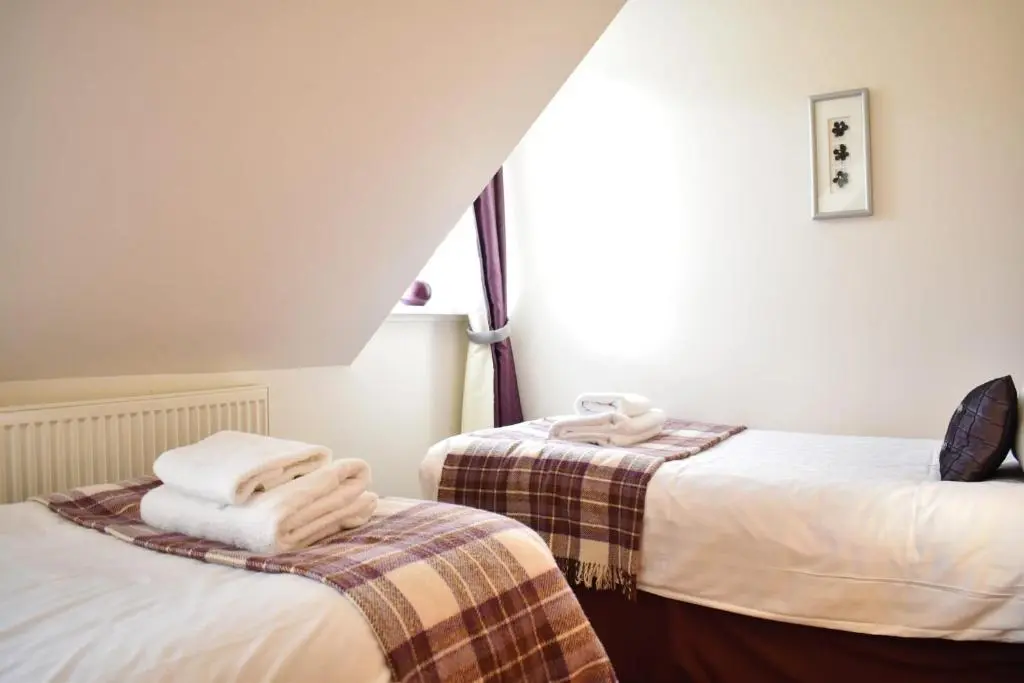 a room with two beds with towels on them at The Ross 2 bedroom apartment in historic Abbey in Fort Augustus