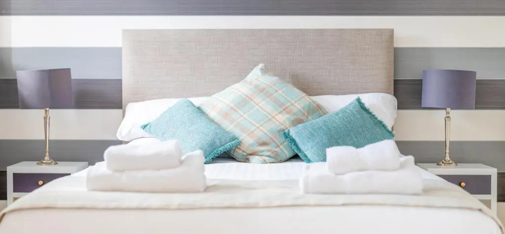 a white bed with pillows on it with two lamps at Monastery apartment with Loch Ness view in Fort Augustus