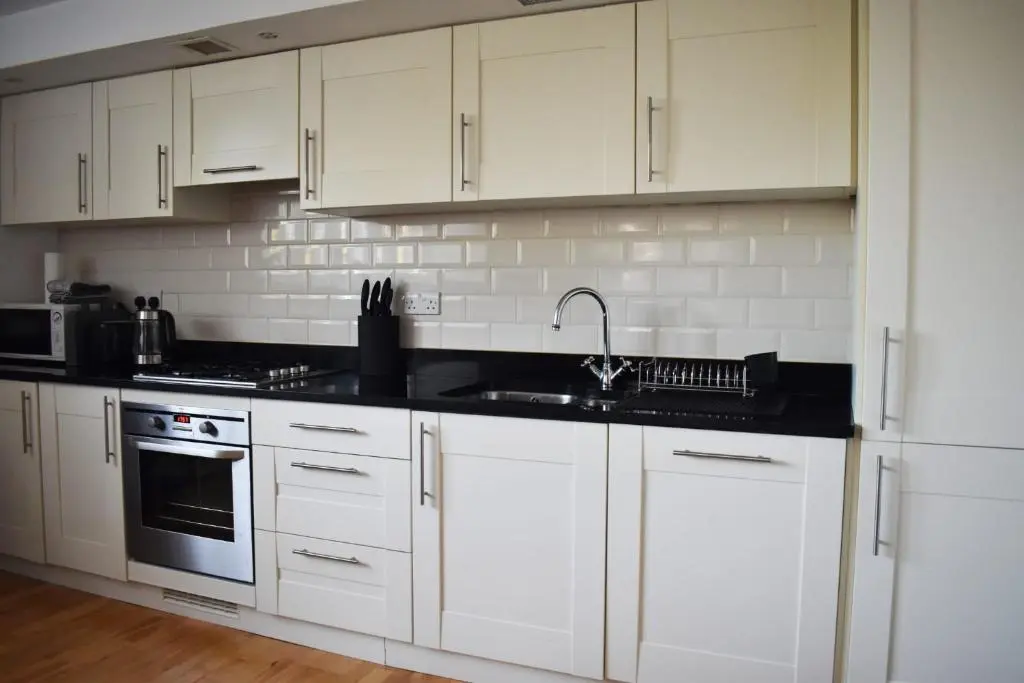 a kitchen with white cabinets and a sink at Monastery apartment with Loch Ness view in Fort Augustus