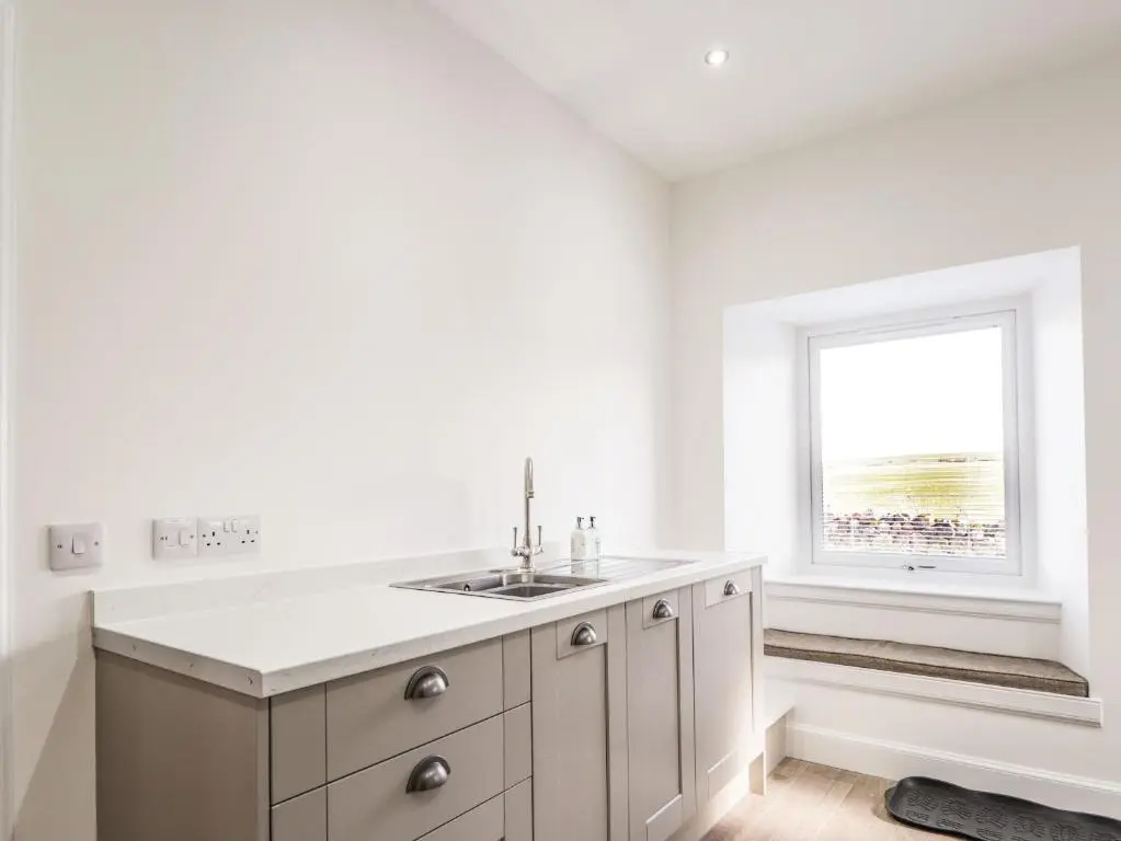 a white kitchen with a sink and a window at Firthview in Nairn