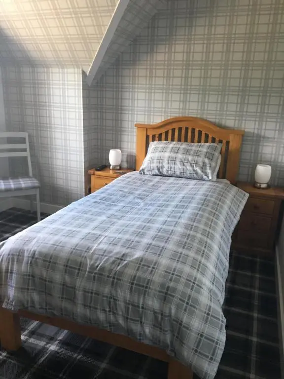 a bedroom with a bed with a plaid comforter at Glenshee Guest House in Golspie