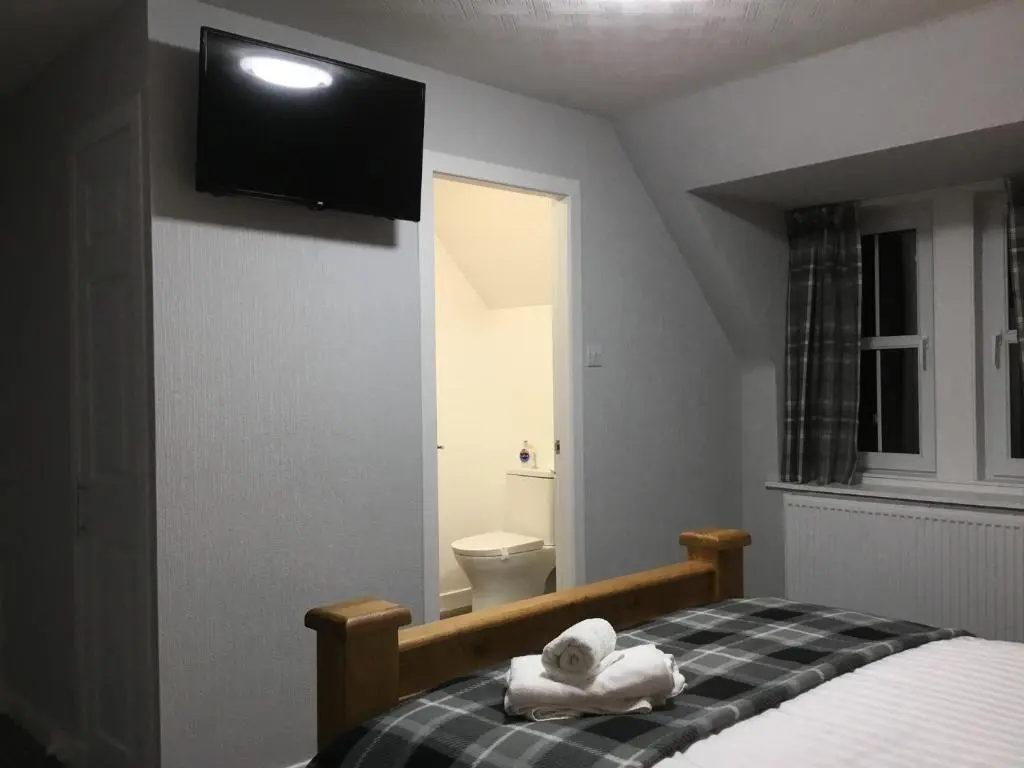 a bedroom with a bed with towels on it at Glenshee Guest House in Golspie
