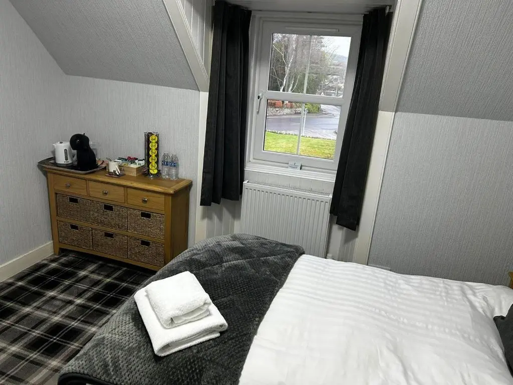 a bedroom with a bed and a window and a dresser at Glenshee Guest House in Golspie
