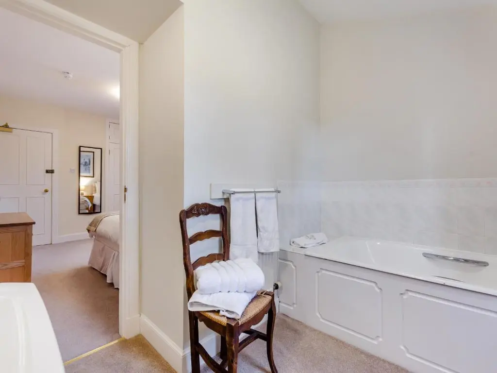 a bathroom with a chair and a bath tub at Cruives Lodge in Kiltarlty