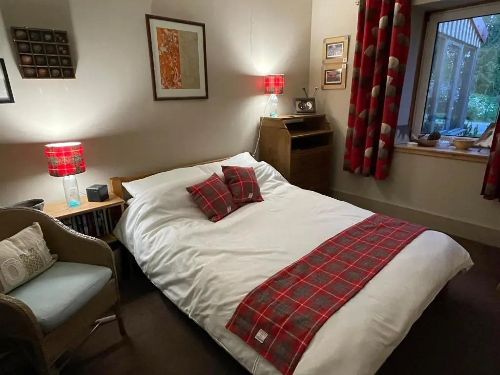 a bedroom with a bed with a blanket and a chair at One bed cosy Highland cottage near Beauly in Beauly
