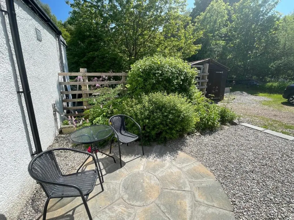 a patio with two chairs and a table and a fence at One bed cosy Highland cottage near Beauly in Beauly