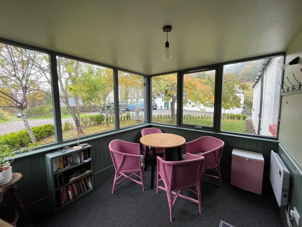 a room with a table and chairs and windows at One bed cosy Highland cottage near Beauly in Beauly