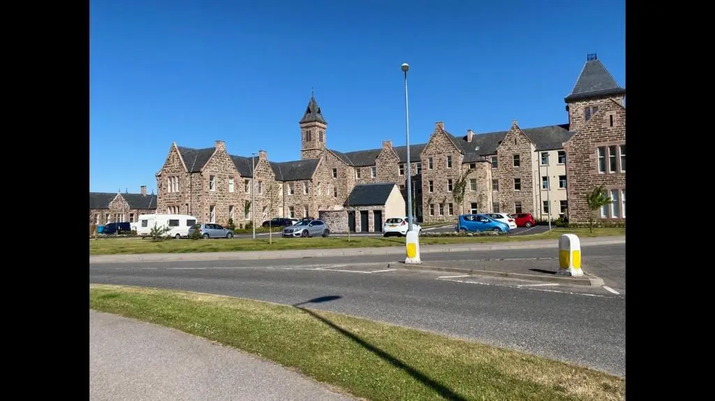 a large brick building with cars parked in front of it at Hiltula spacious premium apartment with beautiful views in Inverness