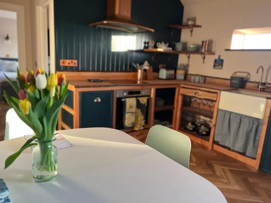 a kitchen with a table with a vase of flowers on it at Osprey Hide in Forres