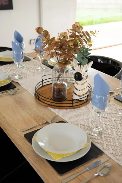 a table with a white plate and a vase of flowers at A Stunning State Of The Art Eco Home - Games Room in Westhill