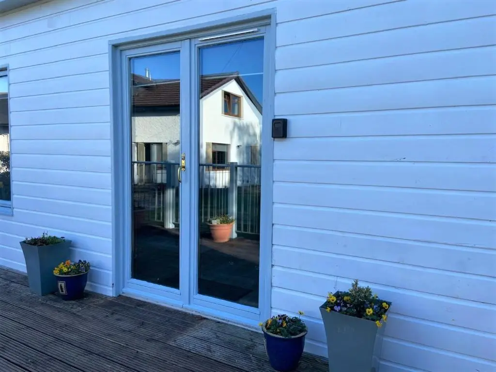 a sliding glass door on a house with potted plants at Chalet on the Green - Self Contained with parking. in Inshes