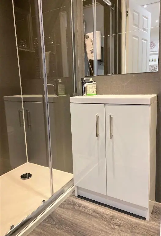 a bathroom with a white cabinet and a mirror at Chalet on the Green - Self Contained with parking. in Inshes