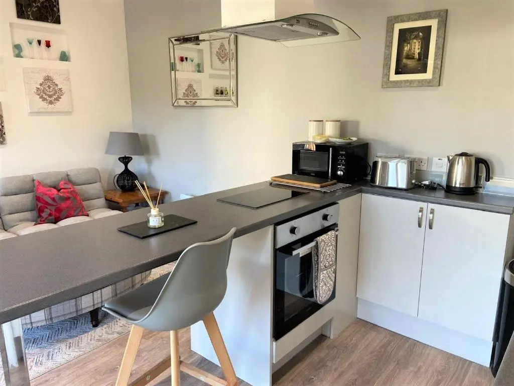 a kitchen with a counter with a microwave and a stove at Chalet on the Green - Self Contained with parking. in Inshes