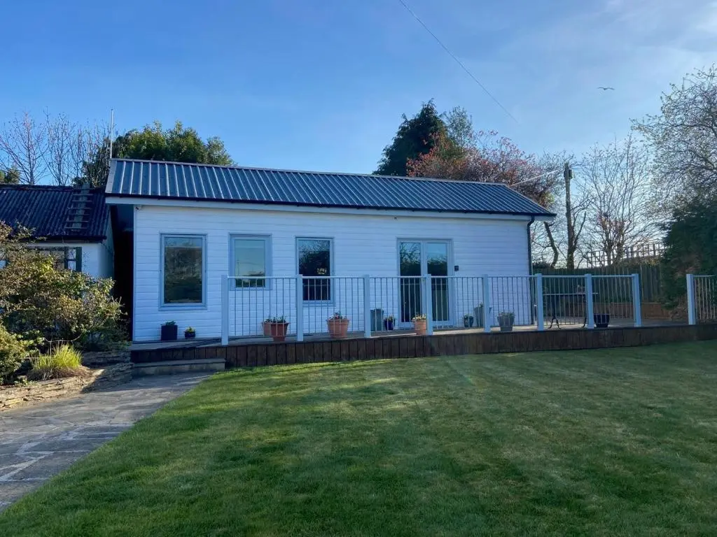 a white house with a fence and a yard at Chalet on the Green - Self Contained with parking. in Inshes