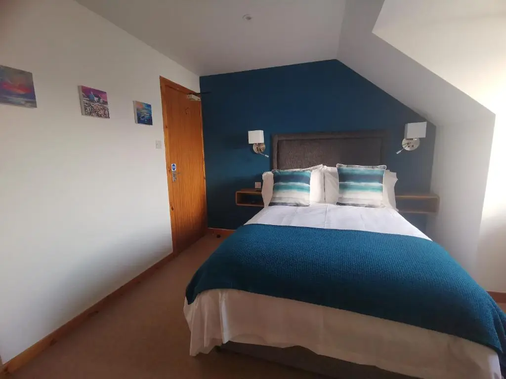 a bedroom with a large bed with a blue wall at Lochbroom Lodge in Ullapool