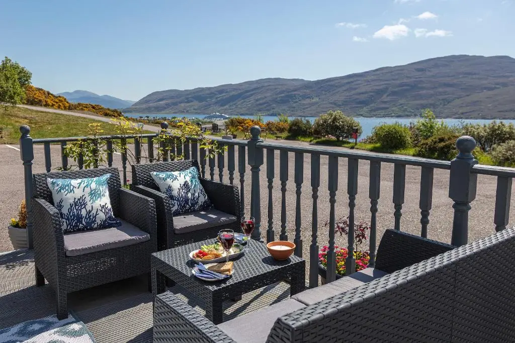 a balcony with two chairs and a table with a bowl of fruit at Lochbroom Lodge in Ullapool