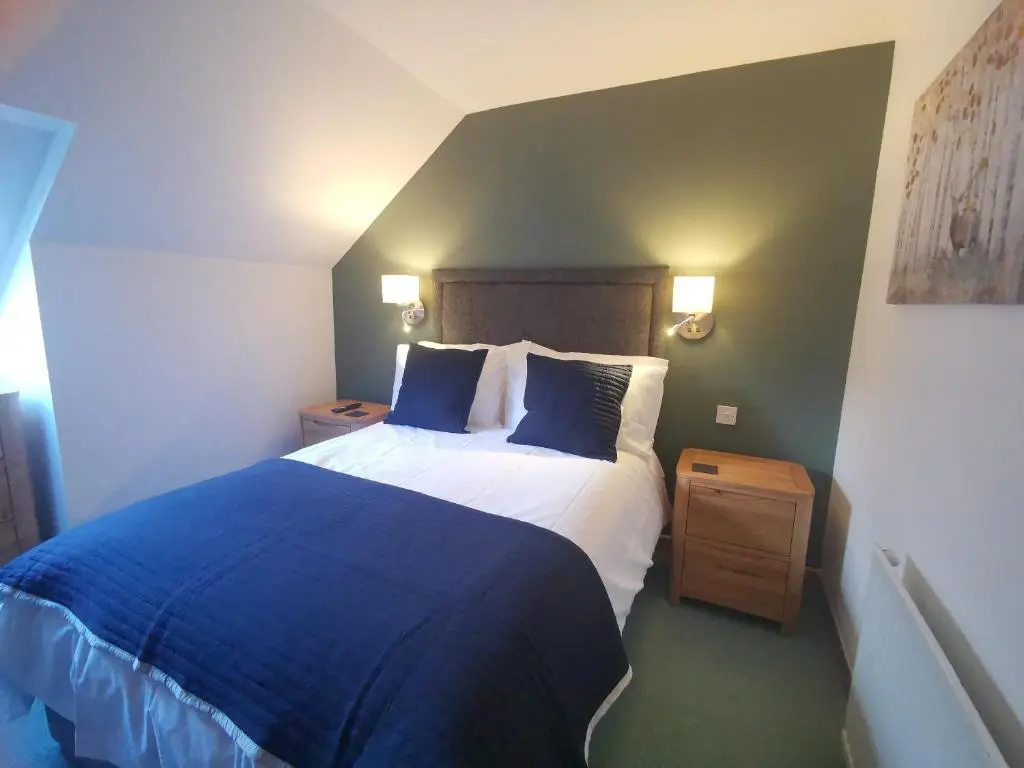 a bedroom with a blue and white bed and two night stands at Lochbroom Lodge in Ullapool