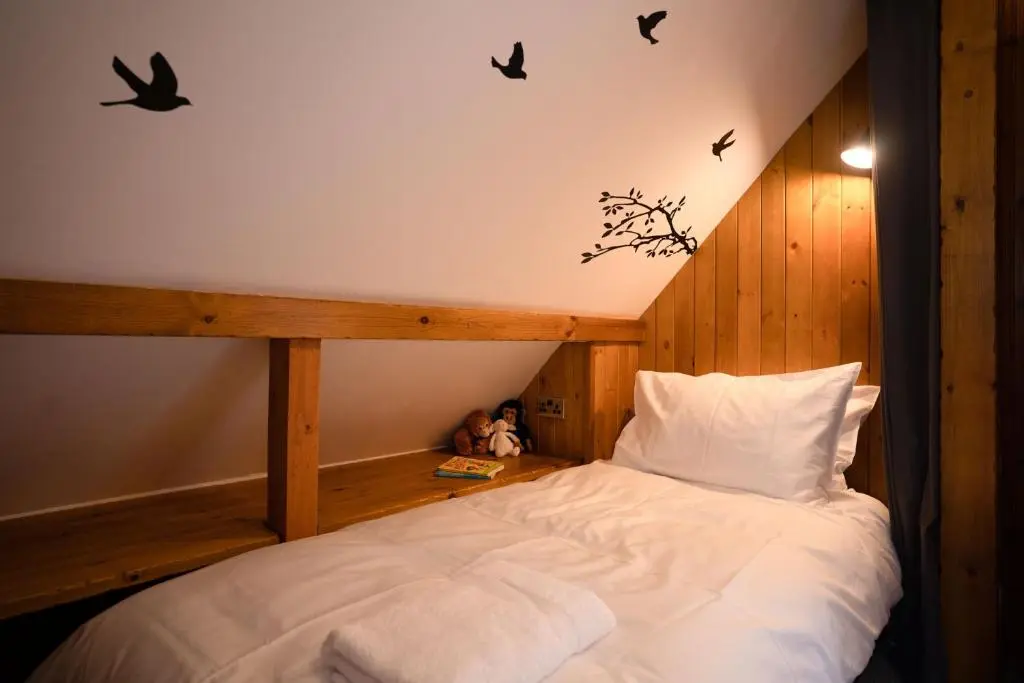 a bedroom with a bed with birds on the wall at The Wilds - Seasgair Lodges in Kingussie