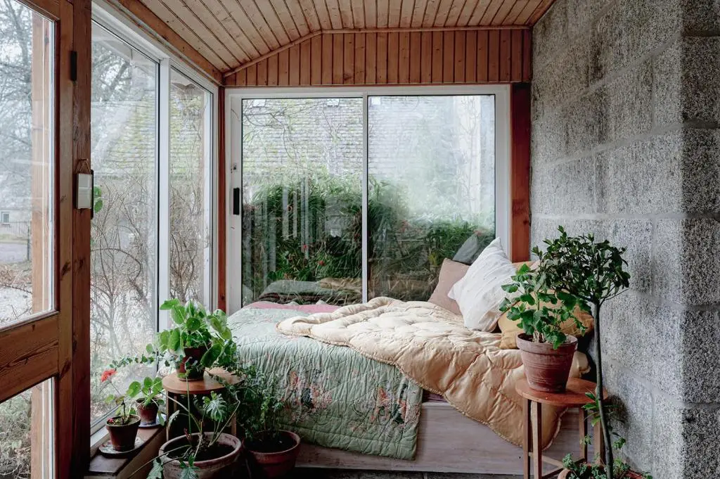 a room with a bed and a window with potted plants at The Dell of Abernethy - A Woodland hideaway in Nethy Bridge