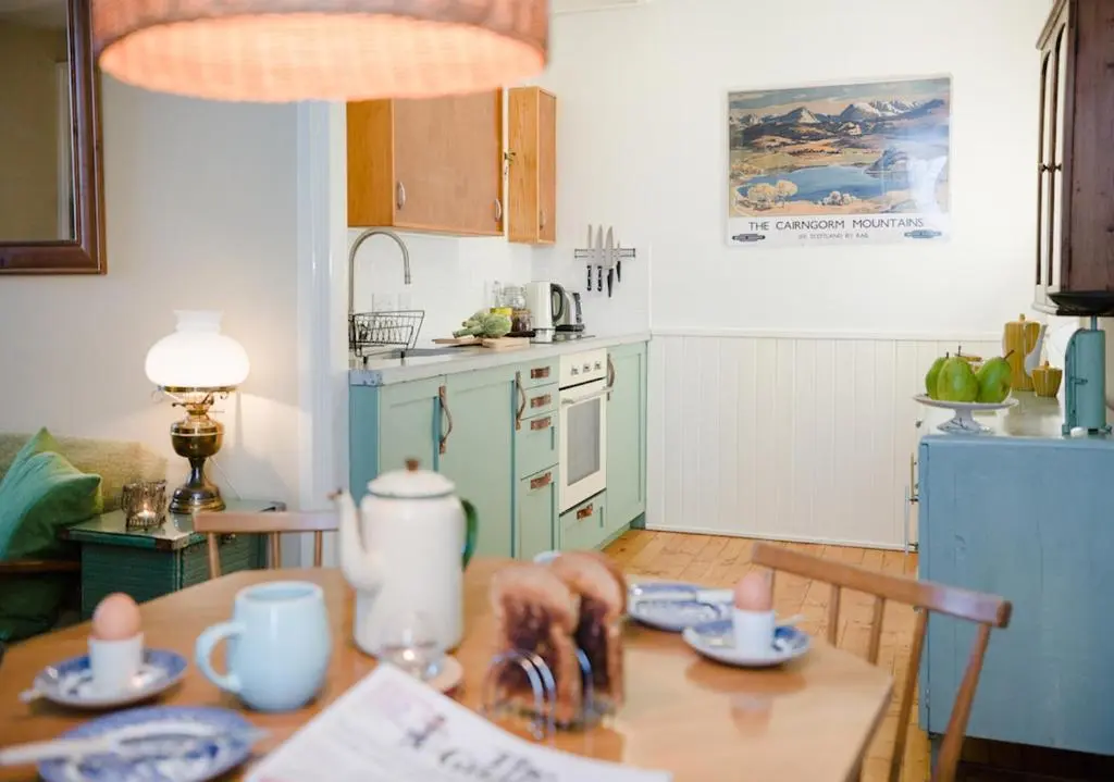 a kitchen with a wooden table and a kitchen with a table at The Dell of Abernethy - A Woodland hideaway in Nethy Bridge