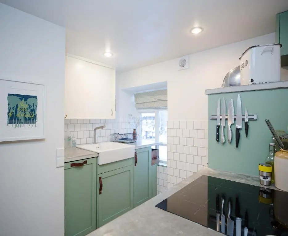 a kitchen with green cabinets and a sink at The Dell of Abernethy - A Woodland hideaway in Nethy Bridge