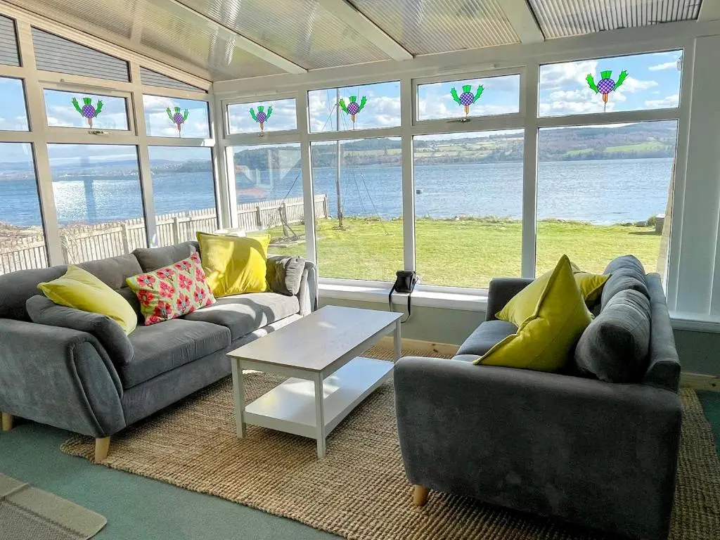 a living room with couches and a table and windows at Spacious Sea View Home 5 miles from Inverness in North Kessock