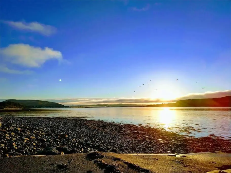 a sunset over a body of water with birds flying at Spacious Sea View Home 5 miles from Inverness in North Kessock