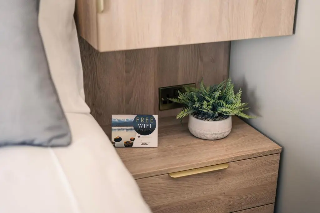 a bedroom with a bed and a plant on a night stand at Sweeney Aviemore One in Aviemore