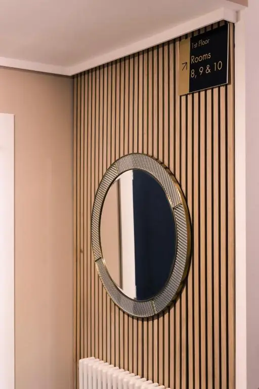 a mirror on a striped wall with a radiator at Sweeney Aviemore One in Aviemore