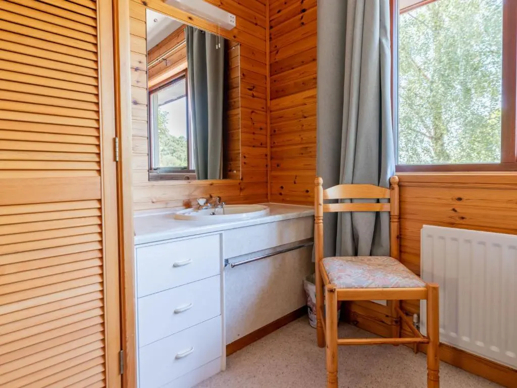 a bathroom with a sink and a chair and a mirror at Holiday Home Achmony Number 9 by Interhome in Drumnadrochit