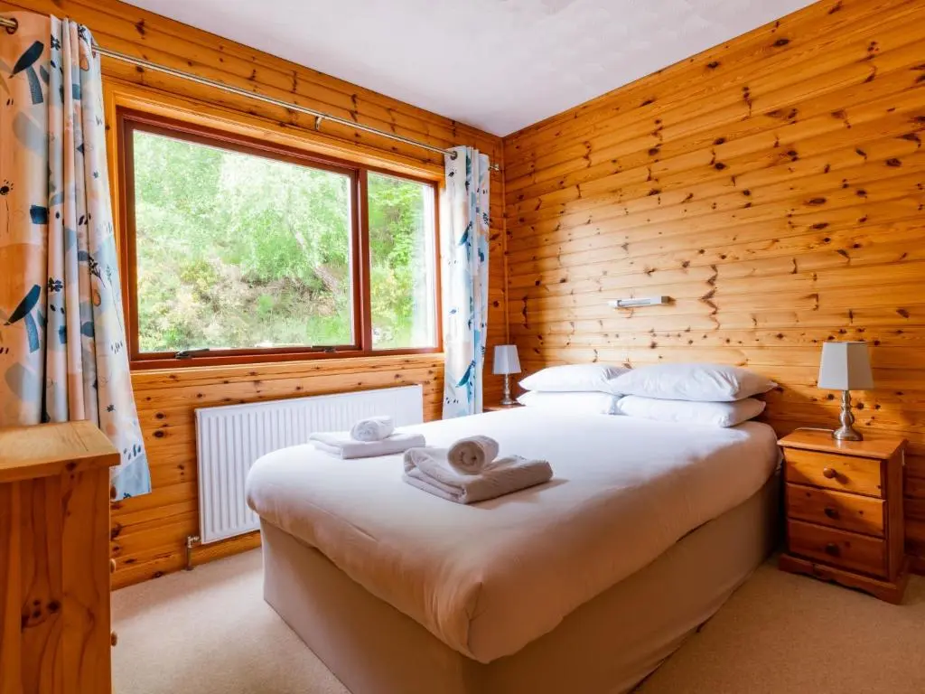 a bedroom with a bed and a wooden wall at Holiday Home Achmony Number 8 by Interhome in Drumnadrochit