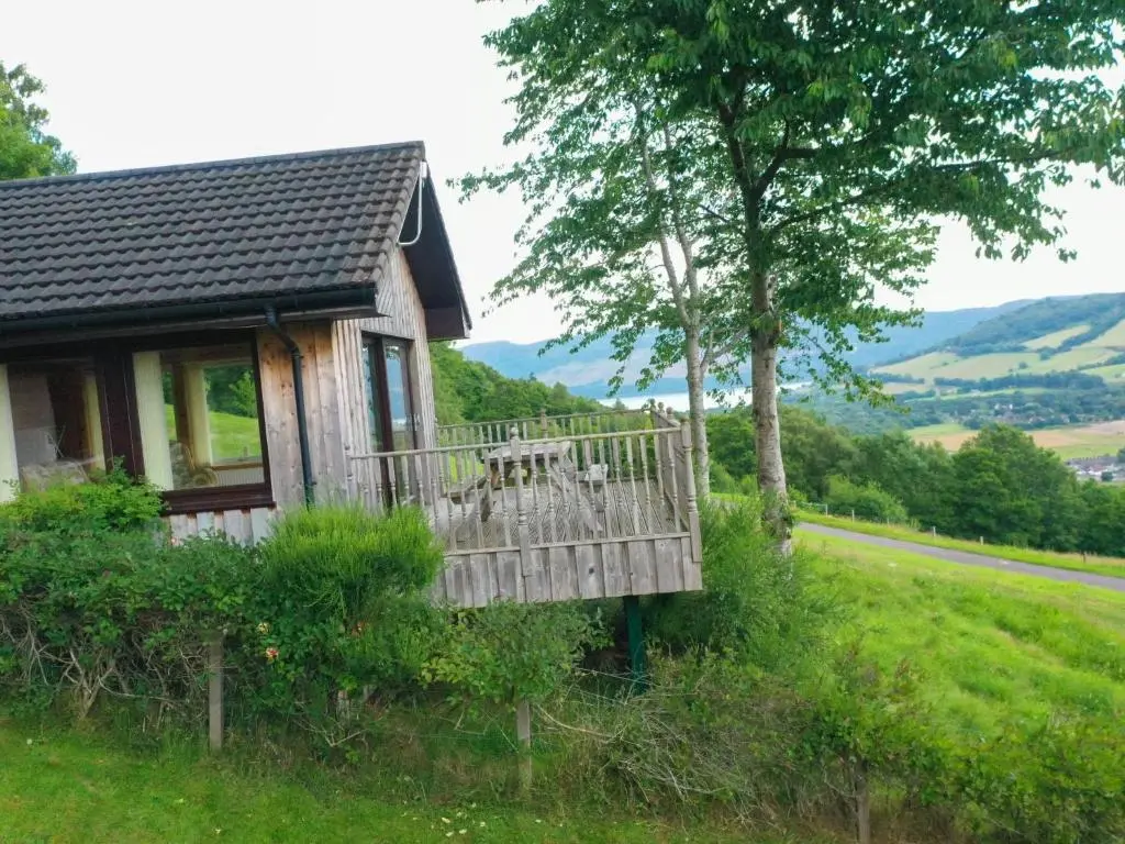 a cabin on a hill with a table on a deck at Holiday Home Achmony Number 8 by Interhome in Drumnadrochit