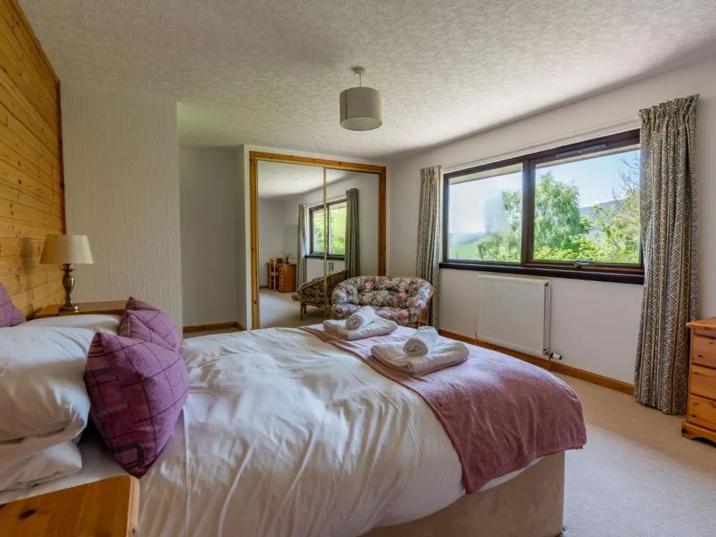 a bedroom with a bed and a large window at Holiday Home Achmony Secluded Westend by Interhome in Drumnadrochit