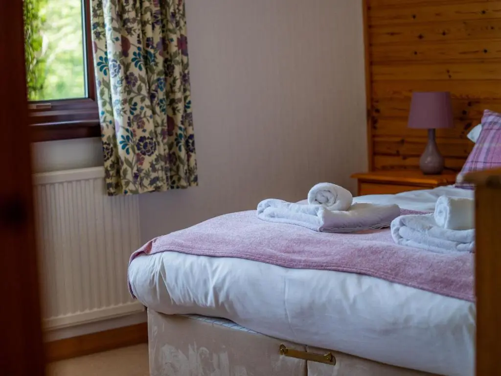 a bedroom with a bed with towels on it at Holiday Home Achmony Secluded Westend by Interhome in Drumnadrochit