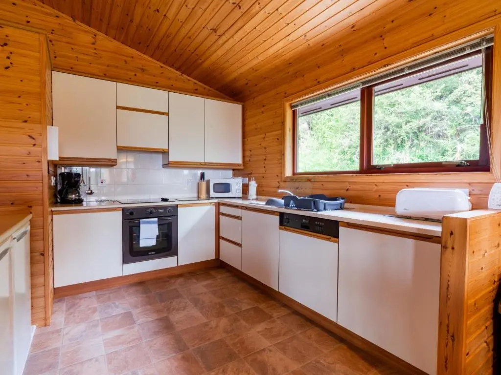 a kitchen with white appliances and a wooden ceiling at Holiday Home Achmony Green by Interhome in Drumnadrochit