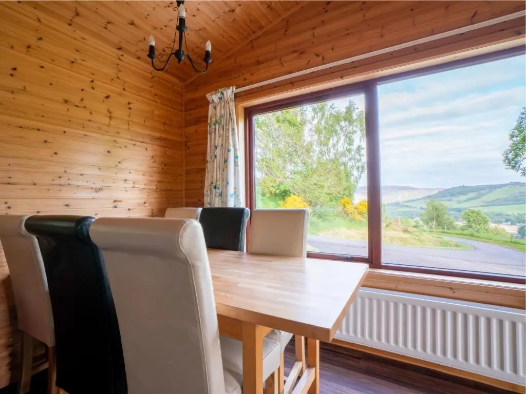 a dining room with a wooden table and a large window at Holiday Home Achmony Byre by Interhome in Drumnadrochit