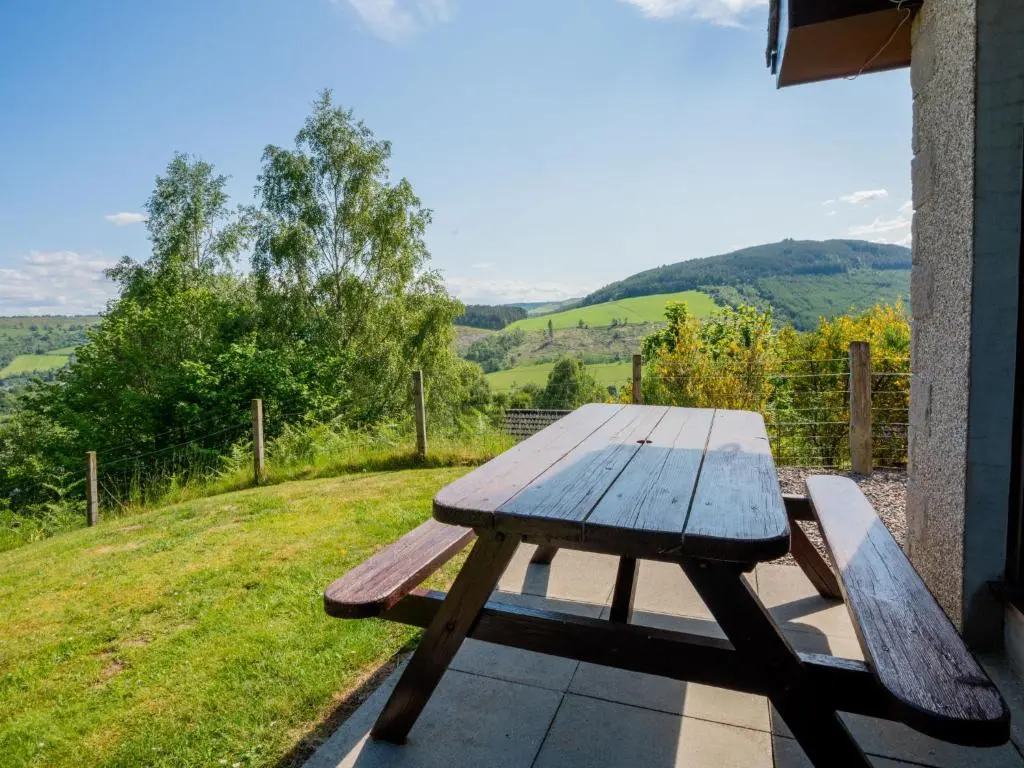 a wooden picnic table sitting on the porch of a house at Holiday Home Achmony Number 10 by Interhome in Drumnadrochit