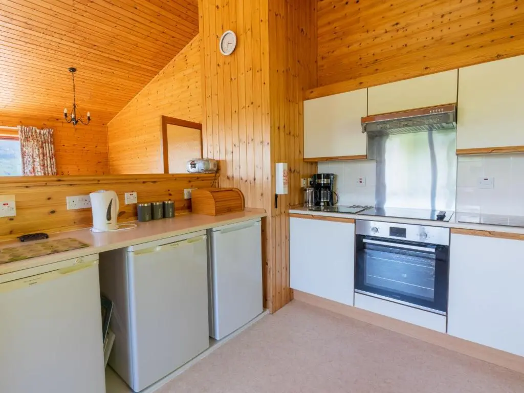 a kitchen with white appliances and wooden walls at Holiday Home Achmony Number 10 by Interhome in Drumnadrochit
