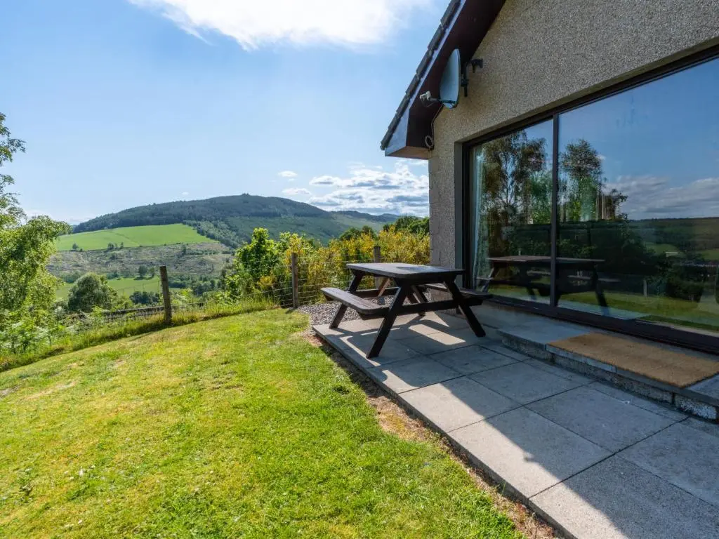 a picnic table on a patio with a view of the mountains at Holiday Home Achmony Number 10 by Interhome in Drumnadrochit