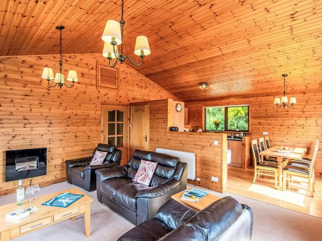 a living room with leather furniture in a log cabin at Holiday Home Achmony Number 11 by Interhome in Drumnadrochit