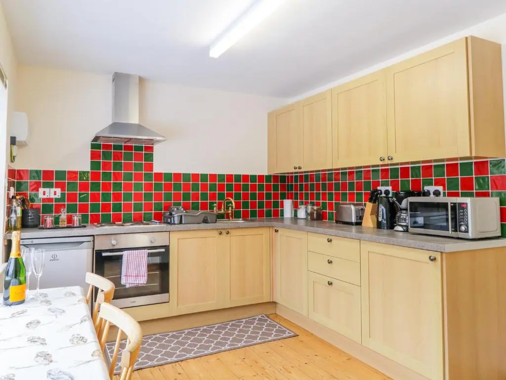 a kitchen with wooden cabinets and red tiles on the wall at The Old Mill in Beauly