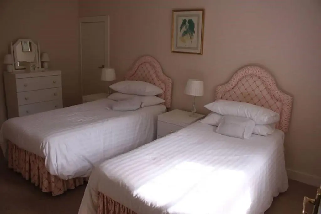 two beds in a bedroom with white sheets at The Delnashaugh in Ballindalloch