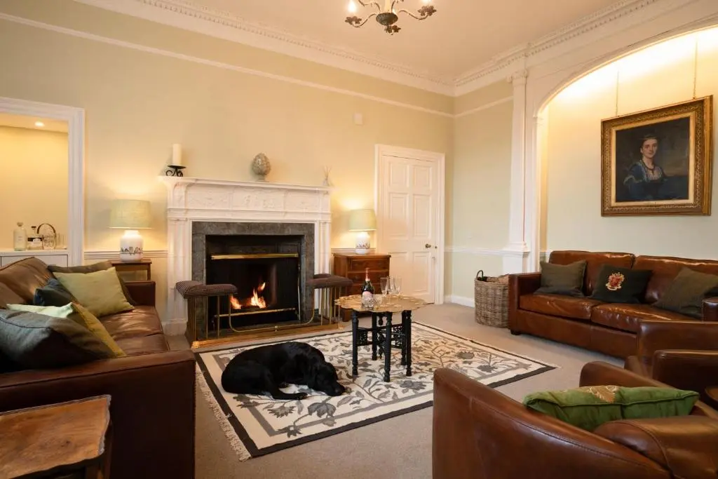 a living room with a dog laying on the floor in front of a fireplace at Kincraig House - Seasgair Lodges in Kincraig