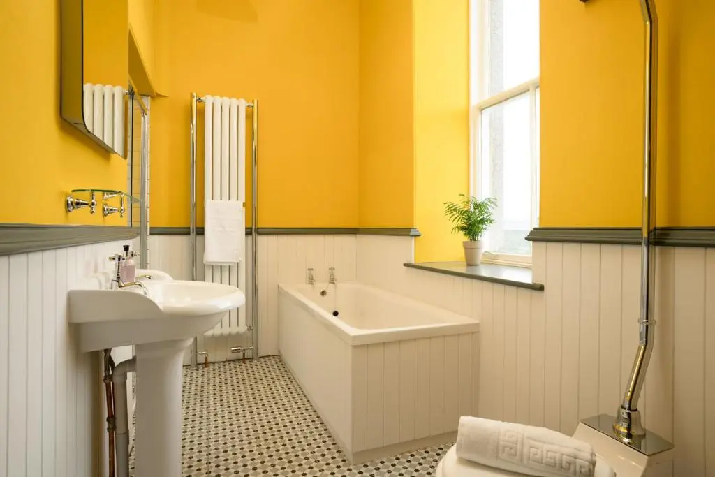 a bathroom with yellow walls and a tub and a sink at Kincraig House - Seasgair Lodges in Kincraig