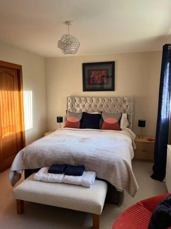 a bedroom with a large bed with red and blue pillows at Bonny Vista in Inverness