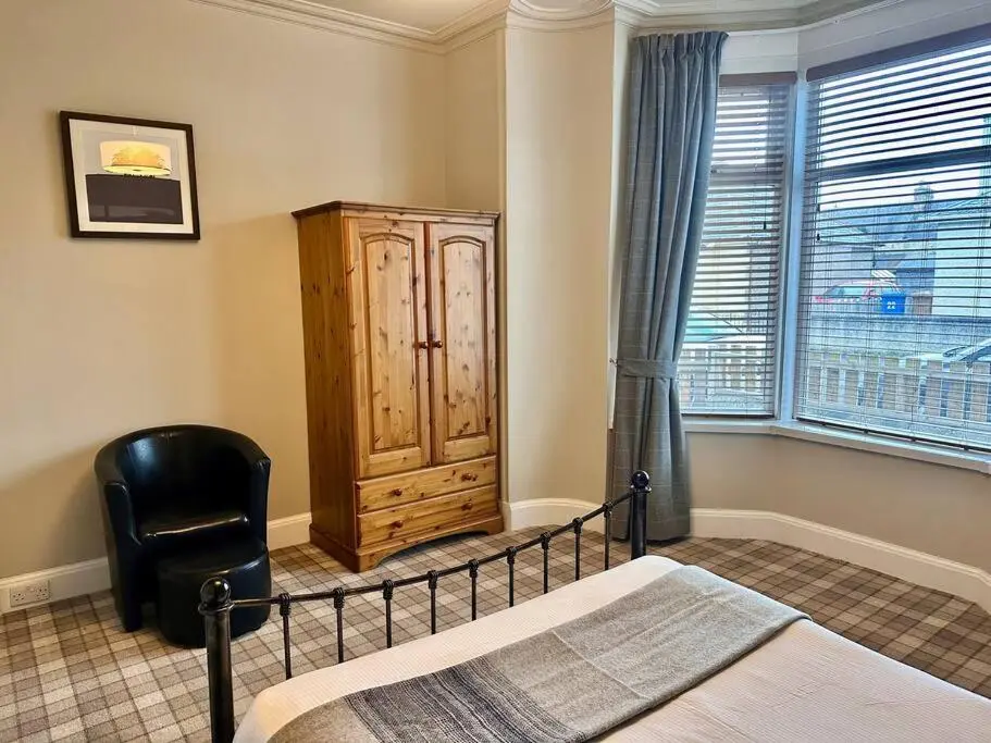 a bedroom with a bed and a chair next to a window at Home Sweet Home, Central in Inverness