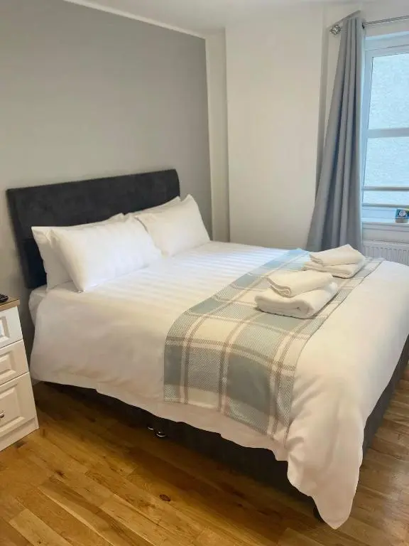 a bedroom with a bed with white sheets and a window at Inverness Highland Apartment in Inverness