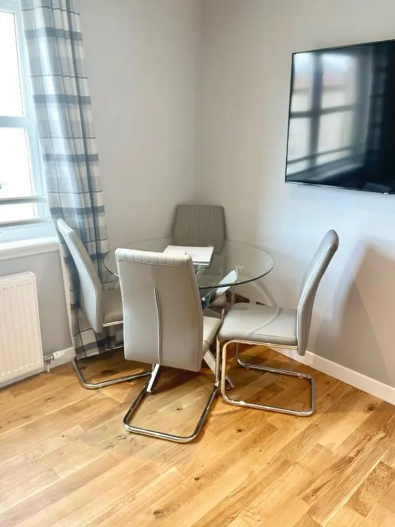 a dining room with a glass table and chairs at Inverness Highland Apartment in Inverness